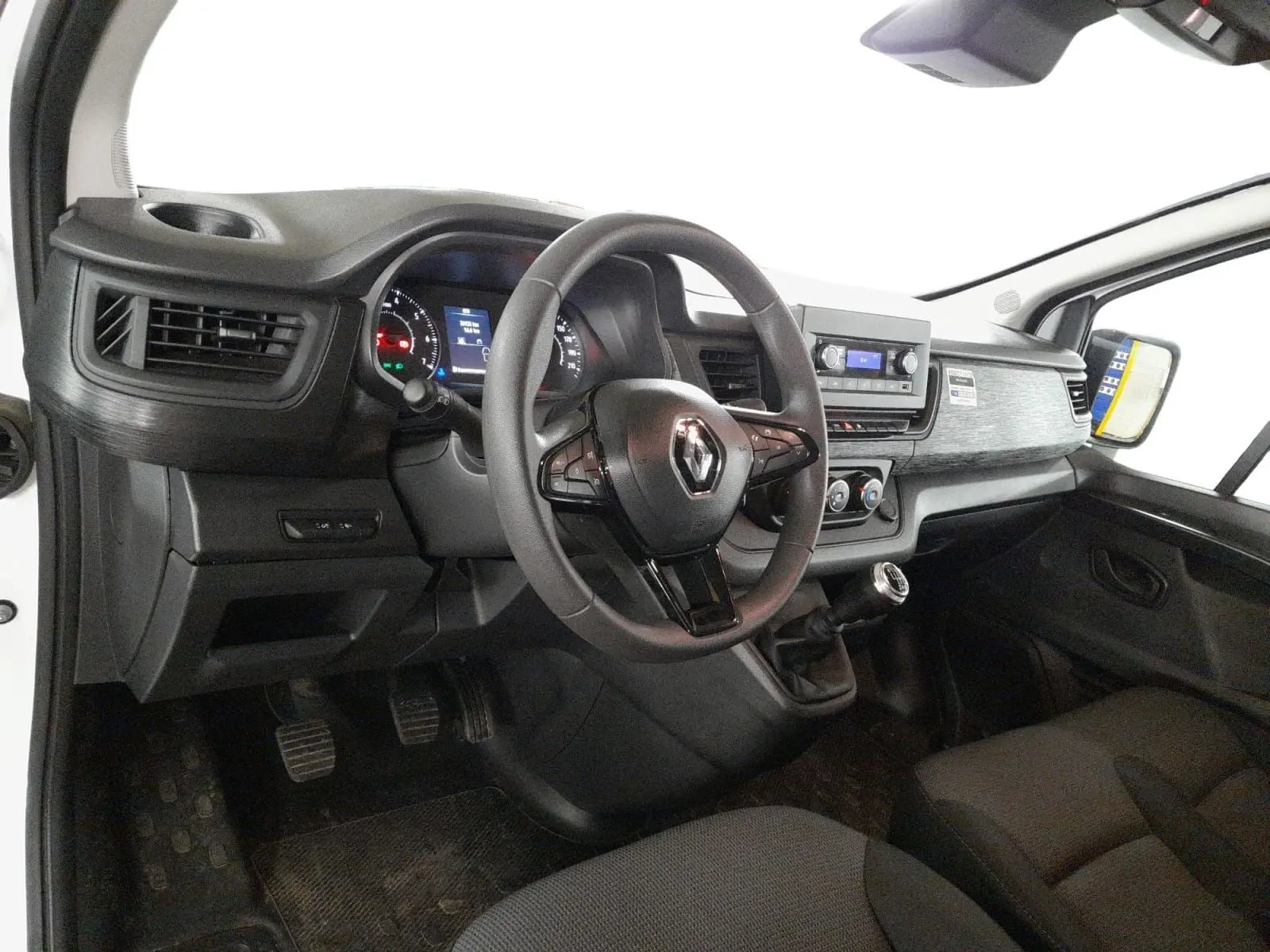 Vue intérieure côté conducteur du Renault Trafic Fourgon 2024, tableau de bord noir avec volant multifonction et levier de vitesse manuel.