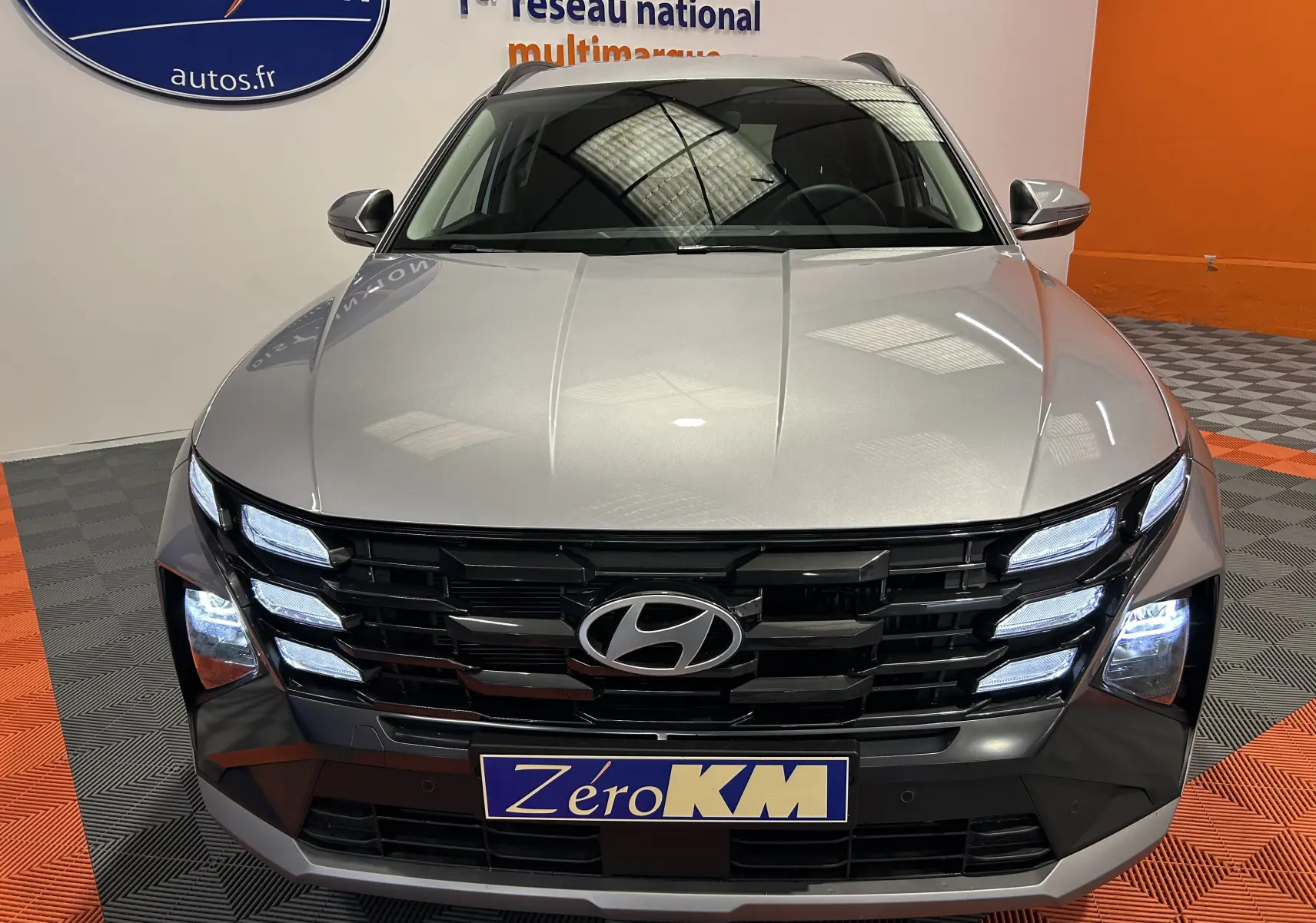 Vue frontale d'un Hyundai Tucson 2025 Shimmering Silver avec phares LED allumés et calandre noire distinctive.