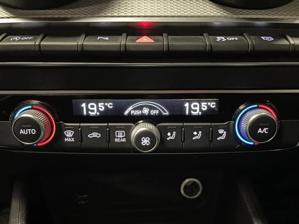 Panneau de climatisation automatique avec réglages à 19,5°C et boutons lumineux dans l'Audi Q2 Business line noir.