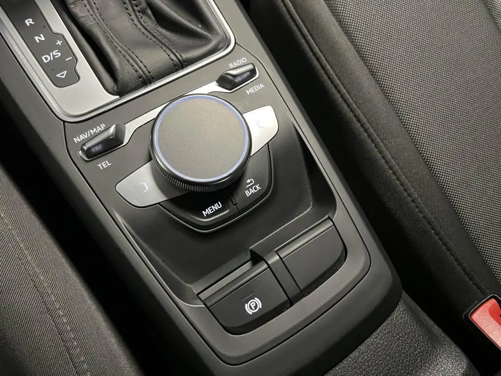 Gros plan sur la console centrale noire de l'Audi Q2 2022 avec molette de commande et levier de boîte automatique.