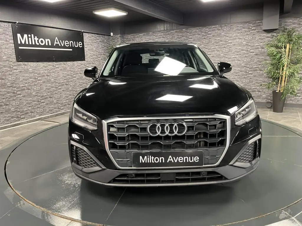 Audi Q2 Business line noir brillant vue de face dans un showroom avec calandre hexagonale et phares LED.