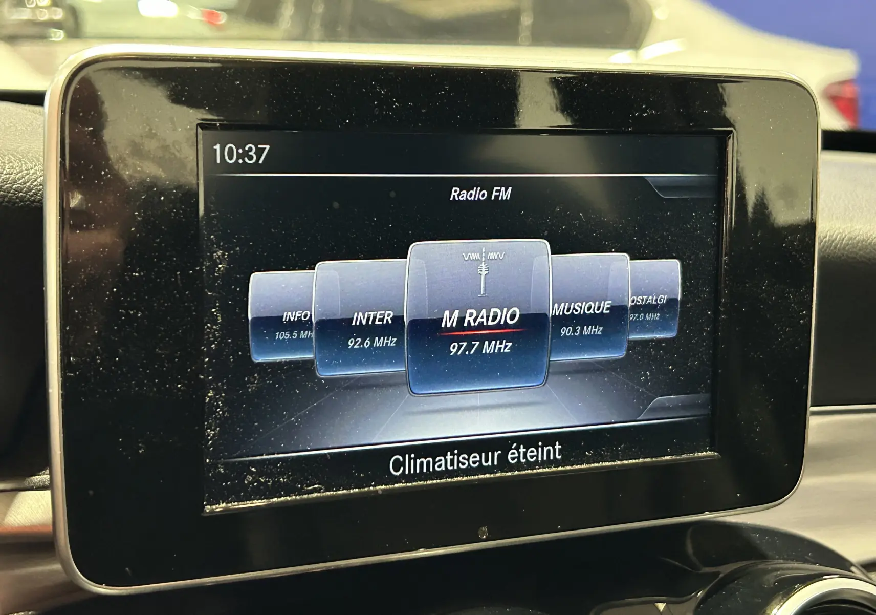 Écran central du système multimédia d'une Mercedes Classe C 200d bleu, affichant la radio FM et l'heure 10:37.