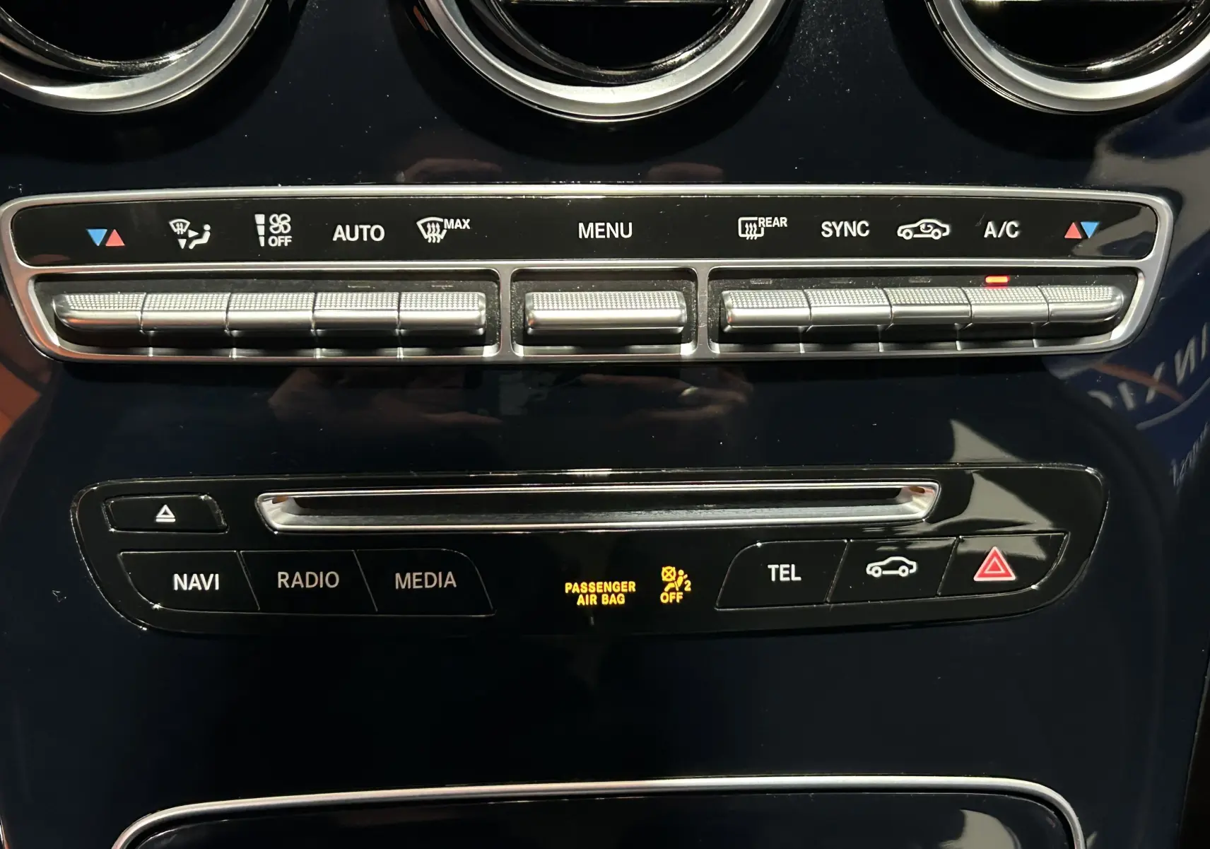 Vue rapprochée de la console centrale noire brillante de la Mercedes Classe C 200d, avec commandes climatisation et multimédia.