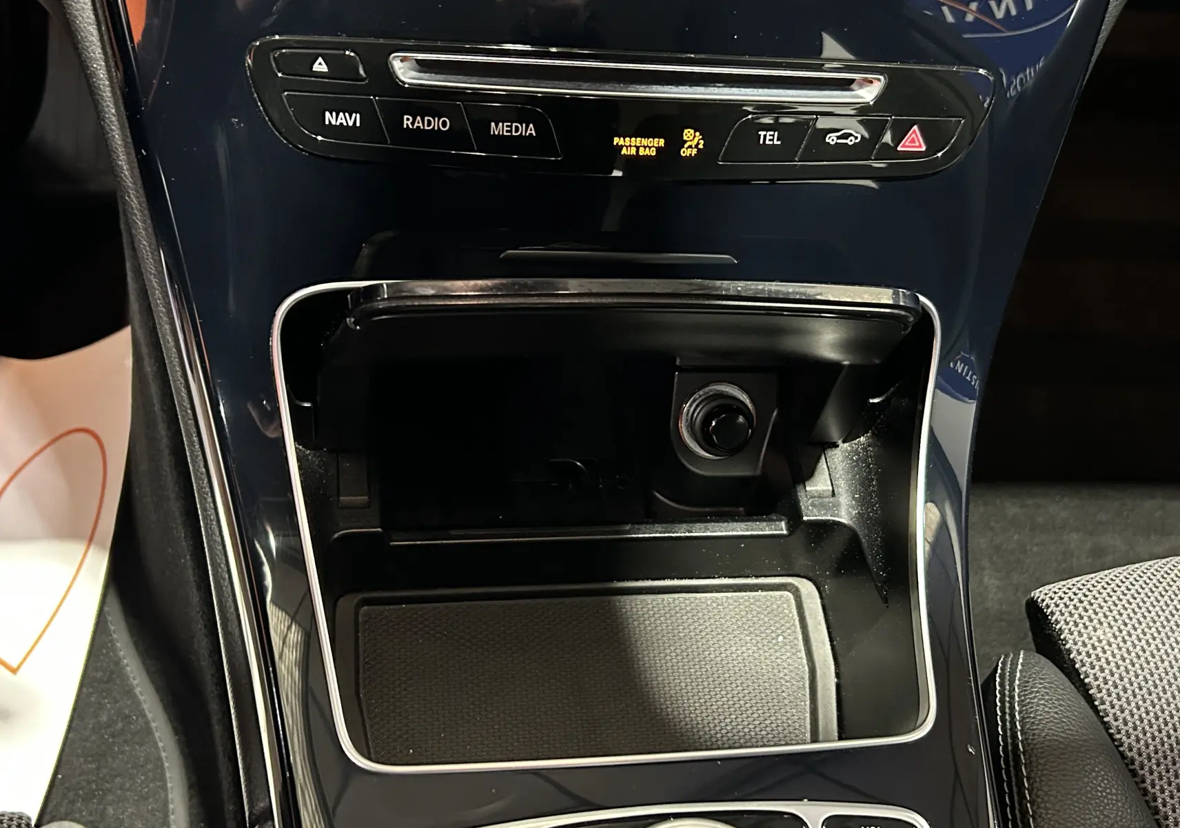 Gros plan sur la console centrale noire brillante de la Mercedes Classe C 200d 2018 avec commandes multimédia et prise allume-cigare.