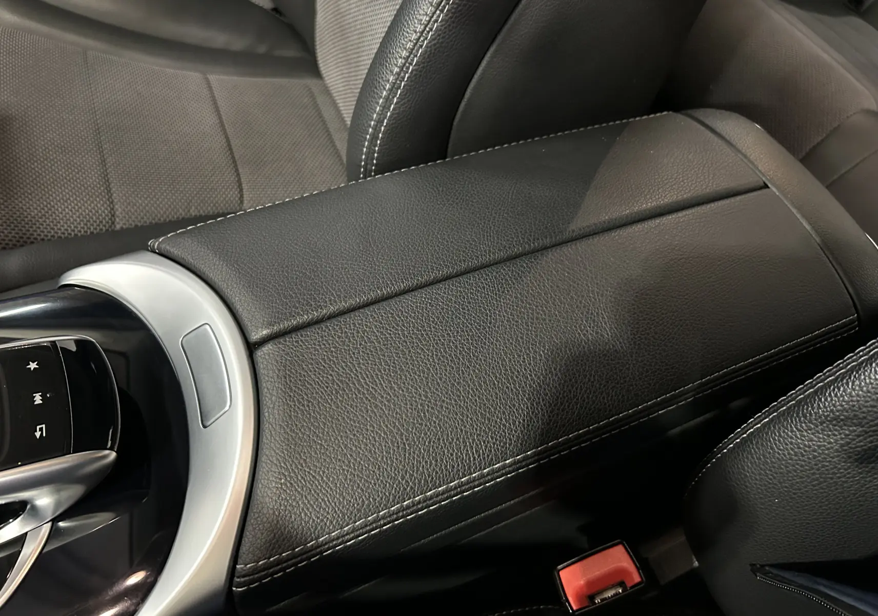 Gros plan sur l'accoudoir central en cuir noir et la console centrale d'une Mercedes Classe C 200d 2018.