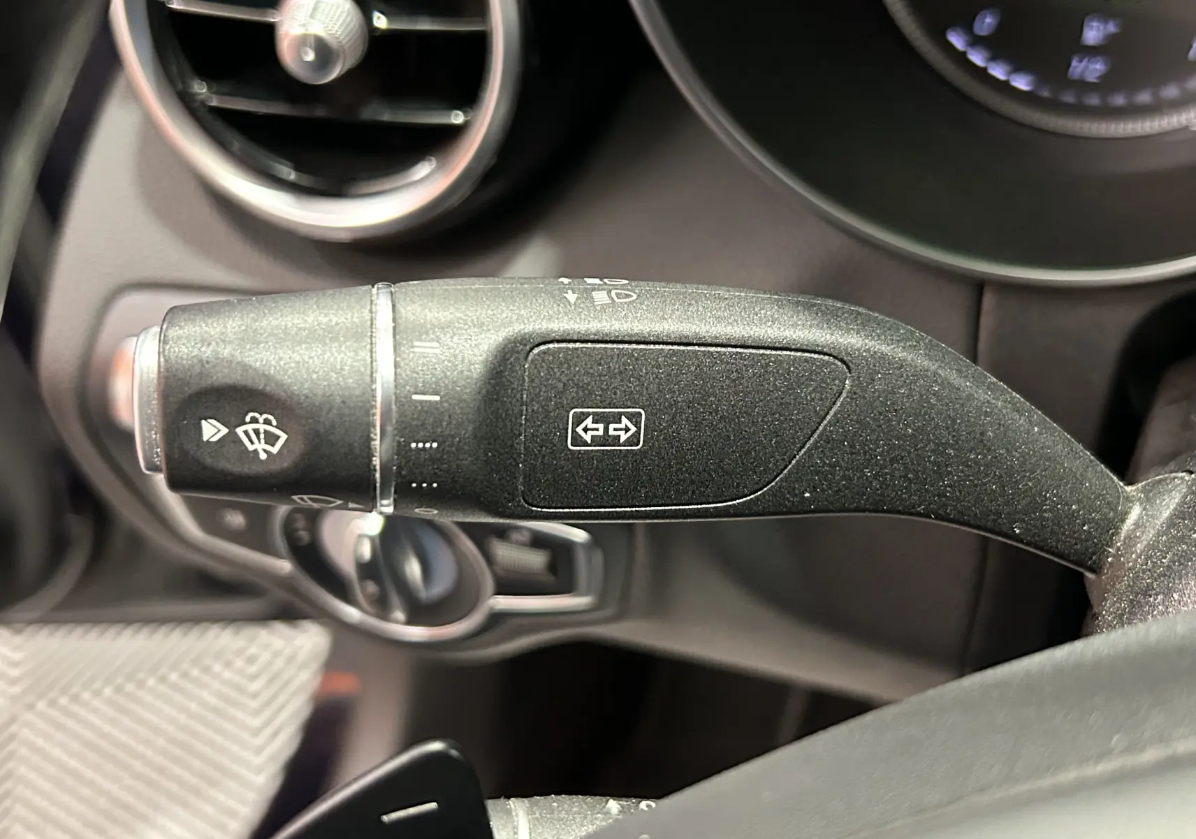 Gros plan sur la commande de clignotant et essuie-glace dans l'habitacle d'une Mercedes Classe C 200d bleue de 2018.