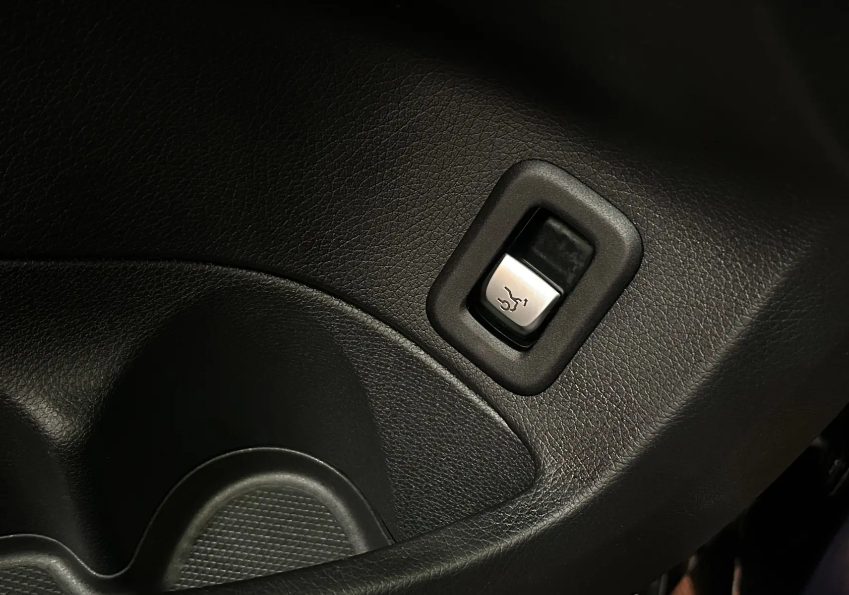 Gros plan sur le bouton d'ouverture électrique du coffre dans l'habitacle d'une Mercedes Classe C 200d bleu 2018.