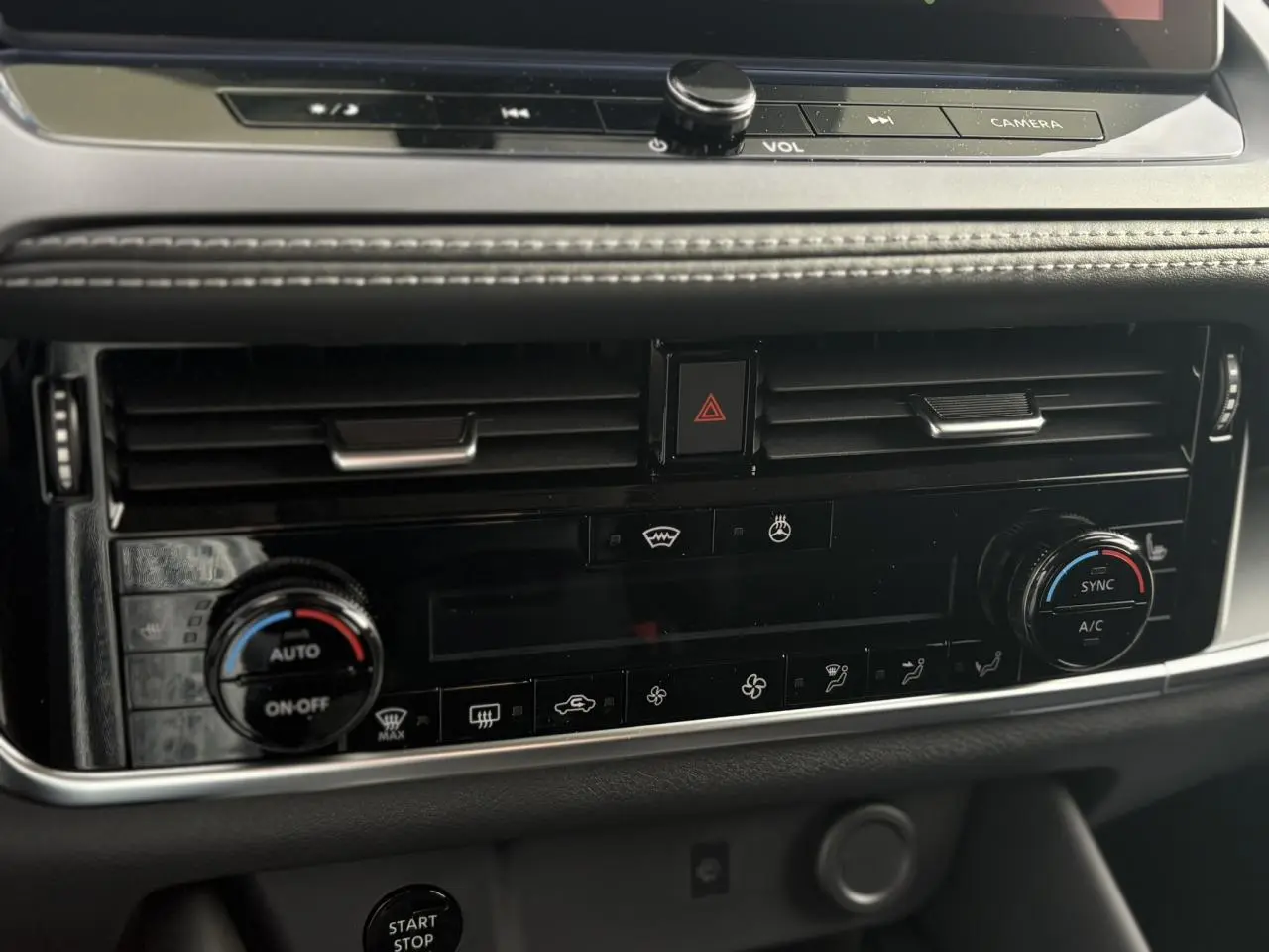 Vue rapprochée du tableau de bord noir du Nissan Qashqai blanc nacré 2025, montrant les commandes de climatisation automatique bi-zone.