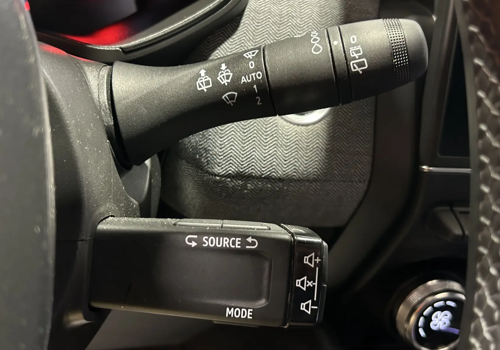 Gros plan sur les commandes au volant côté gauche de la Renault Clio V E-Tech gris Rafale, avec boutons source et mode visibles.