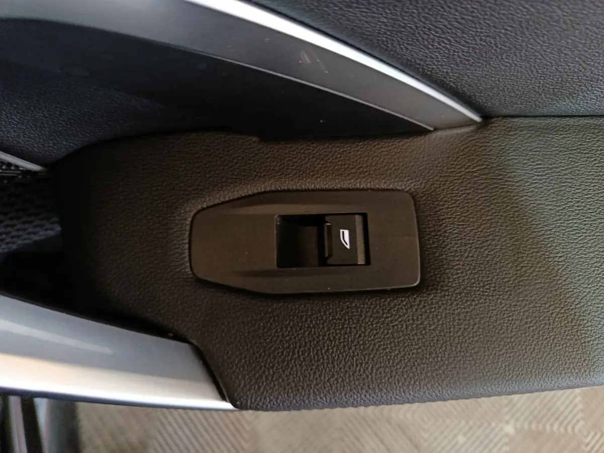 Gros plan sur le bouton de commande de lève-vitre arrière sur la porte intérieure noire d’un BMW X1 xDrive23i M Sport 2023.