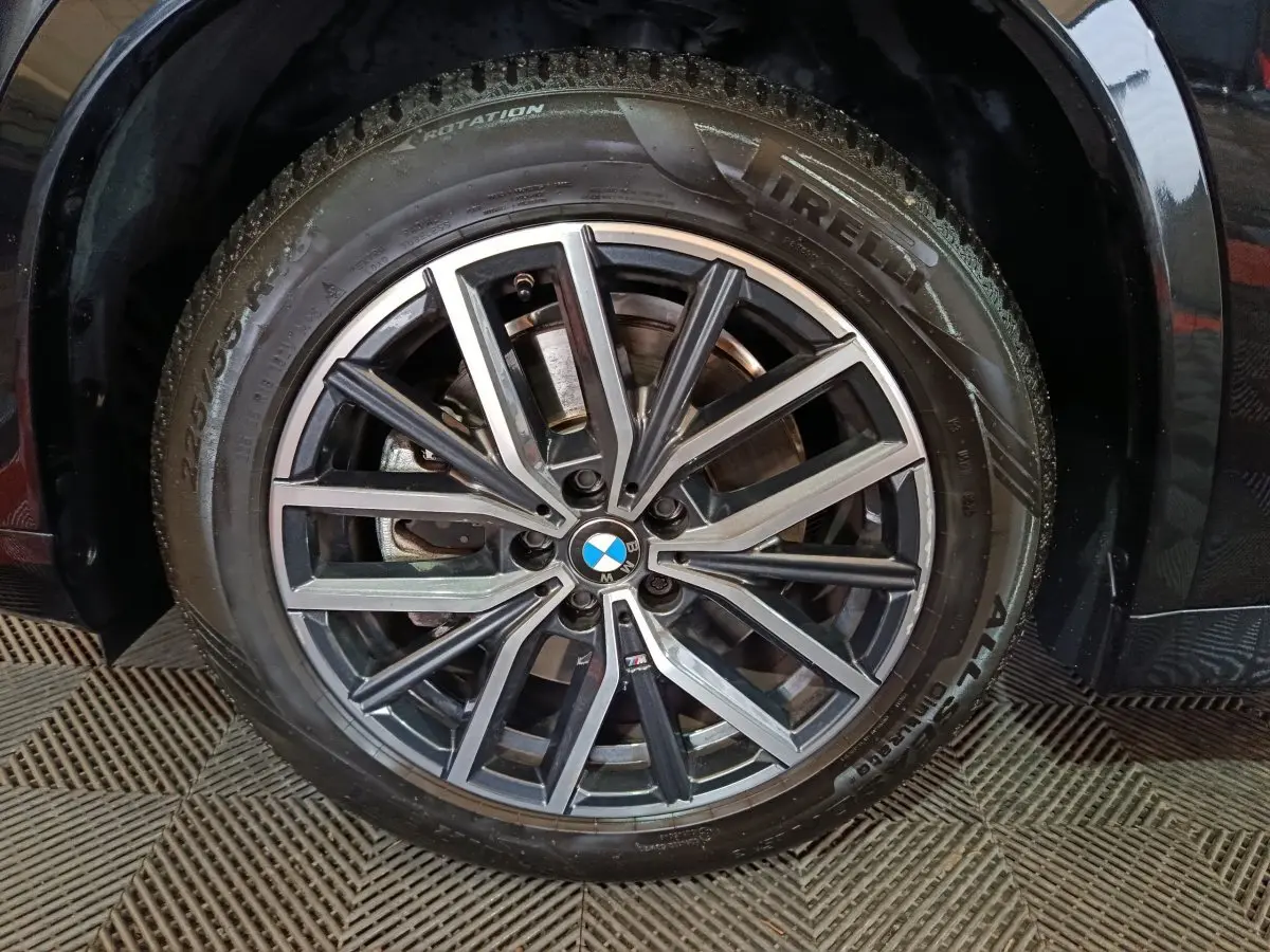 Gros plan sur la roue avant droite noire d’un BMW X1 xDrive23i M Sport avec jante alliage M distinctive.