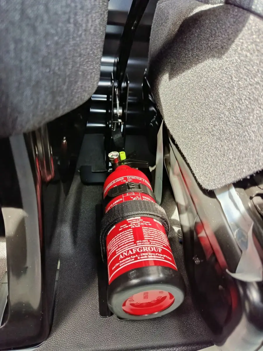 Gros plan sur l’extincteur rouge fixé au sol entre les sièges avant du Renault Master blanc 2025.