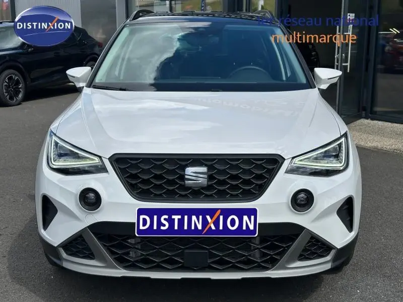 Vue avant d'un SEAT Arona blanc Nevada avec toit noir Minuit, calandre noire et feux LED distinctifs.