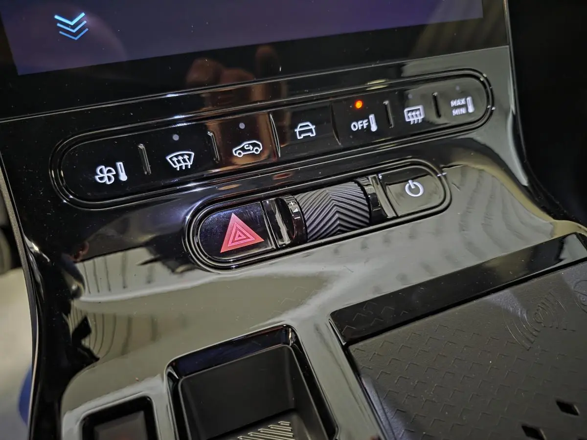 Gros plan sur la console centrale noire brillante du Citroën C5 Aircross 1.2i Hybride avec commandes tactiles et bouton de warning.