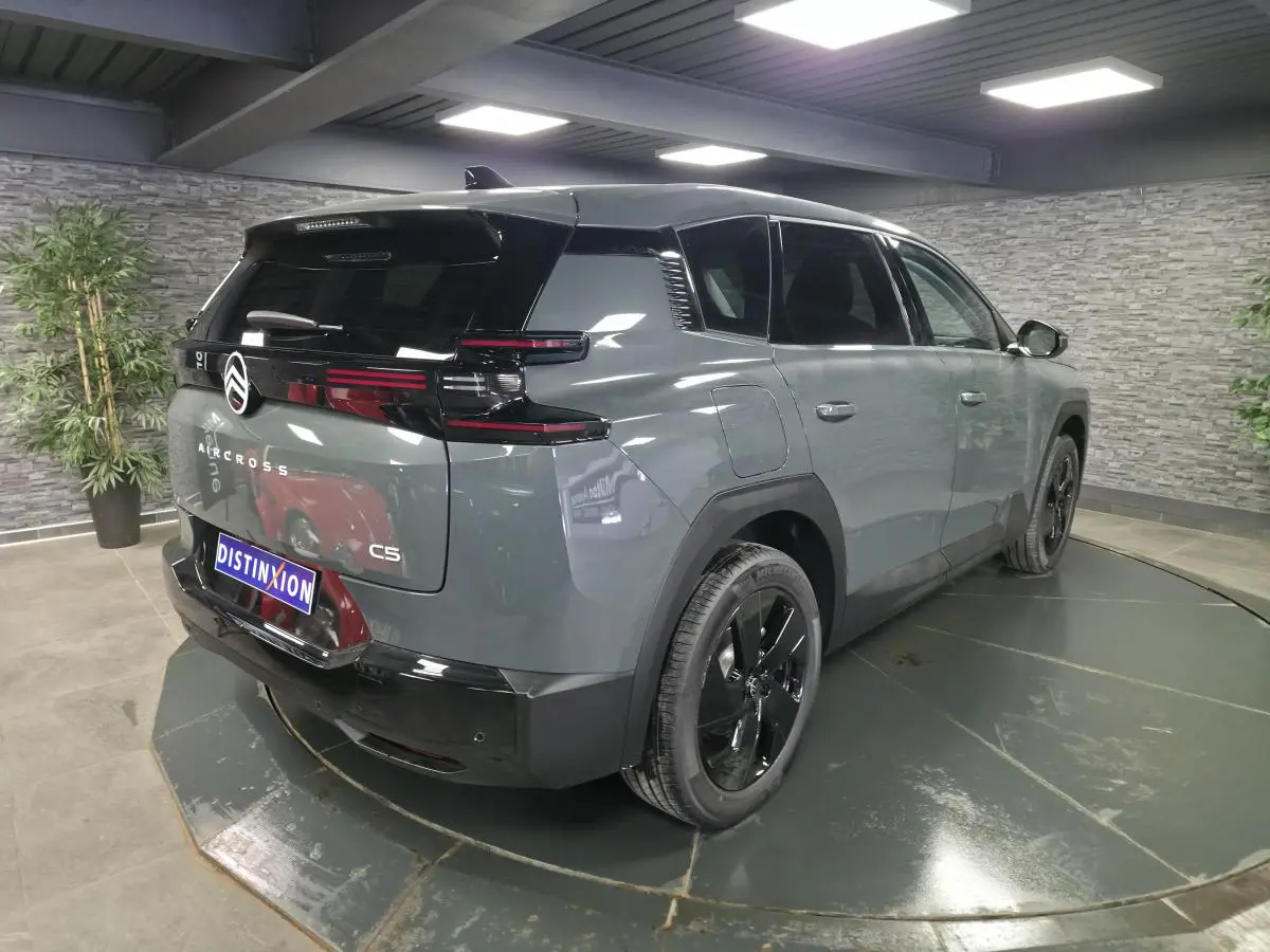 Vue 3/4 arrière droite d'un Citroën C5 Aircross gris métallisé avec toit noir et jantes noires.