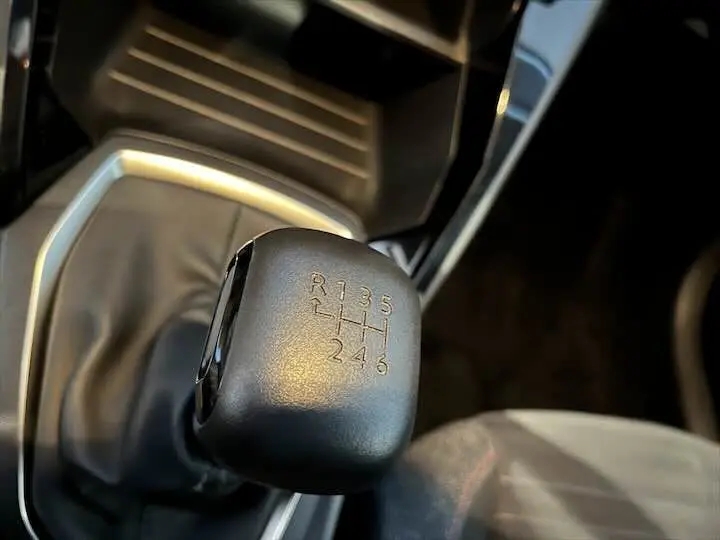 Le levier de vitesses manuel noir de la Peugeot 208 1.5 BlueHDi, vue rapprochée de l'intérieur côté conducteur.