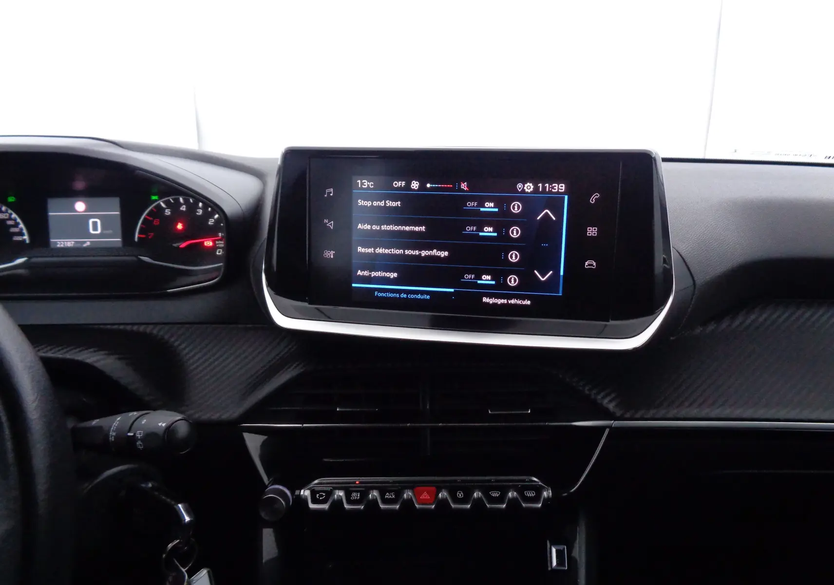 Intérieur du tableau de bord de la Peugeot 208 2020, avec écran tactile central et commandes en rangée sous l'écran.