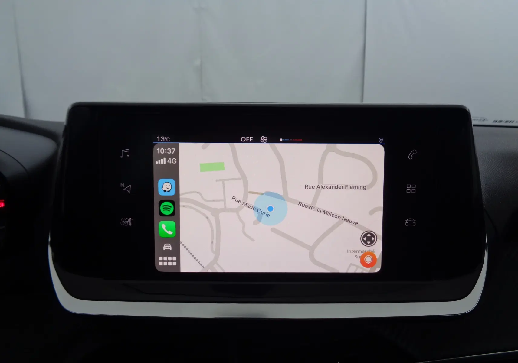 Écran tactile central affichant une carte de navigation dans l'habitacle d'une Peugeot 208 rouge Elixir Metal.