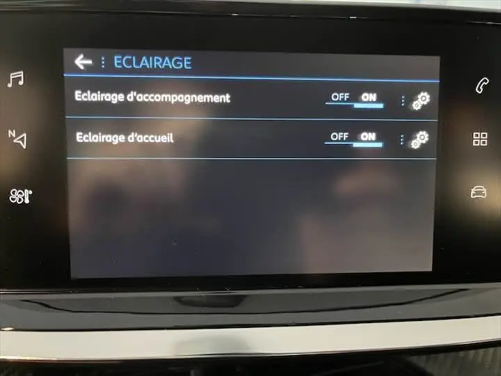 Écran tactile intérieur du Peugeot 208 rouge Elixir Metal montrant les réglages d’éclairage d’accompagnement et d’accueil activés.