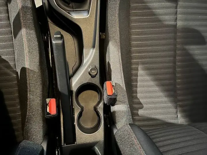 Vue plongeante sur la console centrale et les sièges avant gris foncé de la Peugeot 208 rouge Elixir Metal.