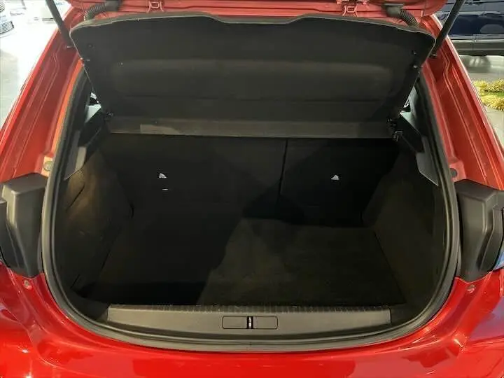 Coffre ouvert vu de l'arrière d'une Peugeot 208 rouge Elixir Metal, montrant l'espace de chargement intérieur.