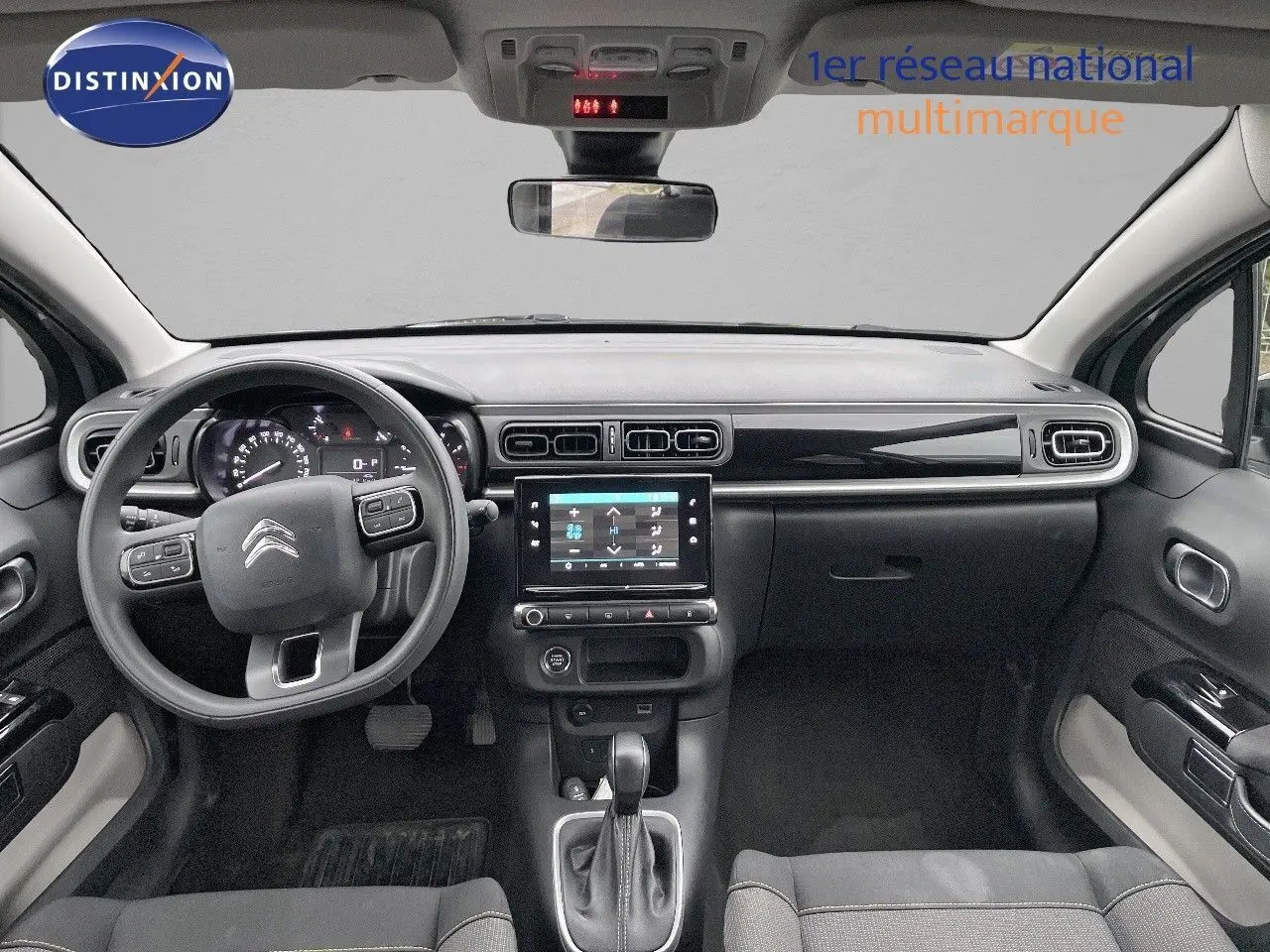 Vue intérieure frontale du tableau de bord et volant du Citroën C3 2023 gris acier avec toit noir et écran tactile central.