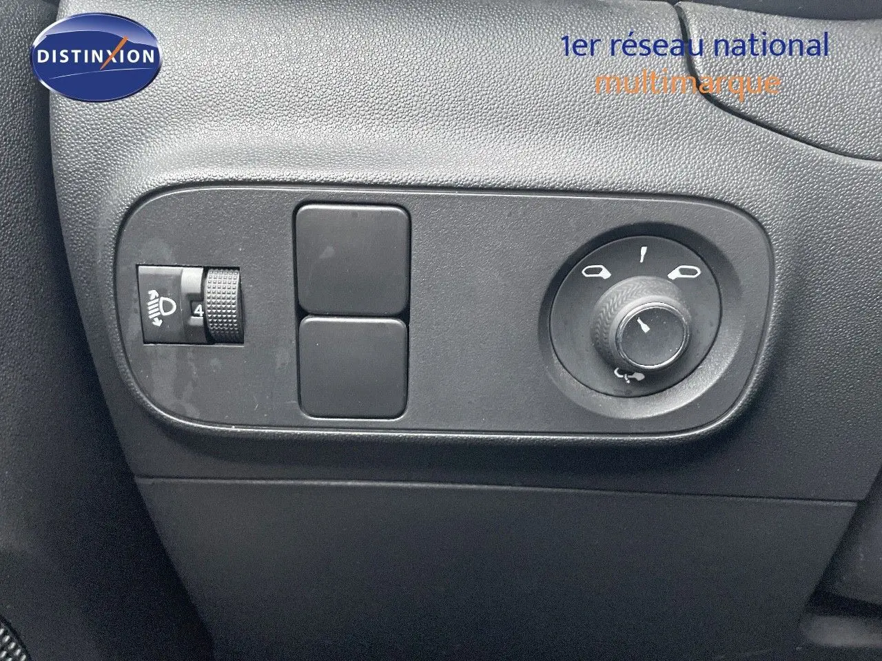 Gros plan sur les commandes de réglage des rétroviseurs et des phares d'une Citroën C3 gris acier toit noir, côté gauche.