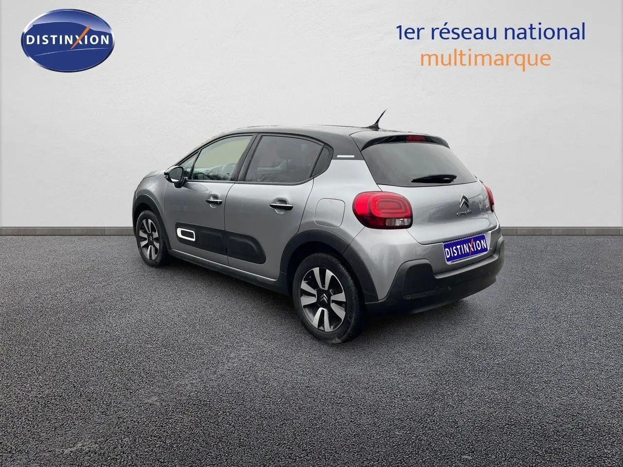 Citroën C3 2023 gris acier métal avec toit noir vue 3/4 arrière côté gauche, jantes bi-ton et protections latérales noires.