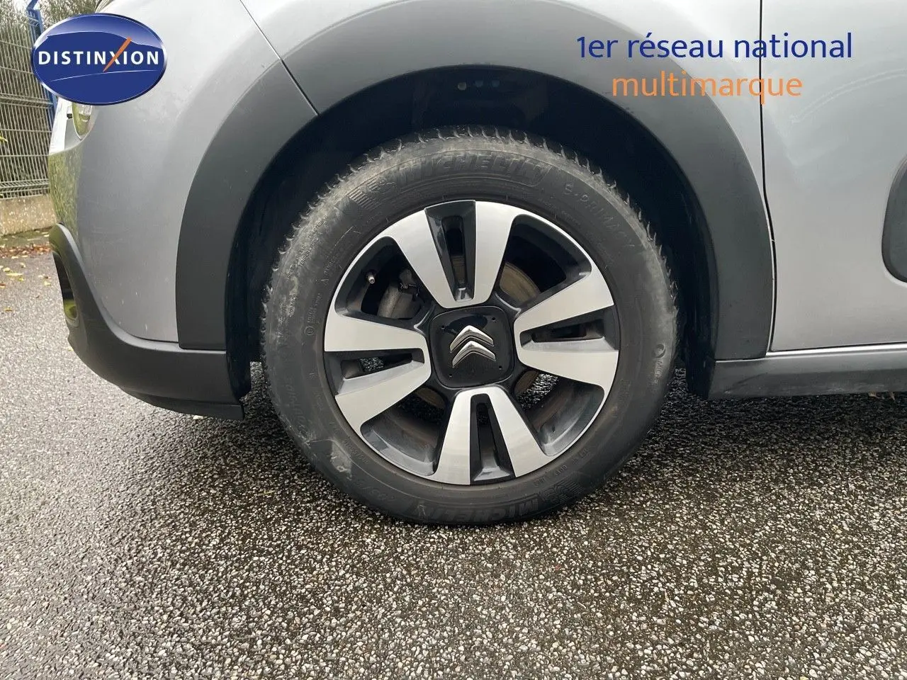 Gros plan sur la roue avant gauche d'une Citroën C3 gris acier métal avec jante alliage bicolore et logo Citroën central.