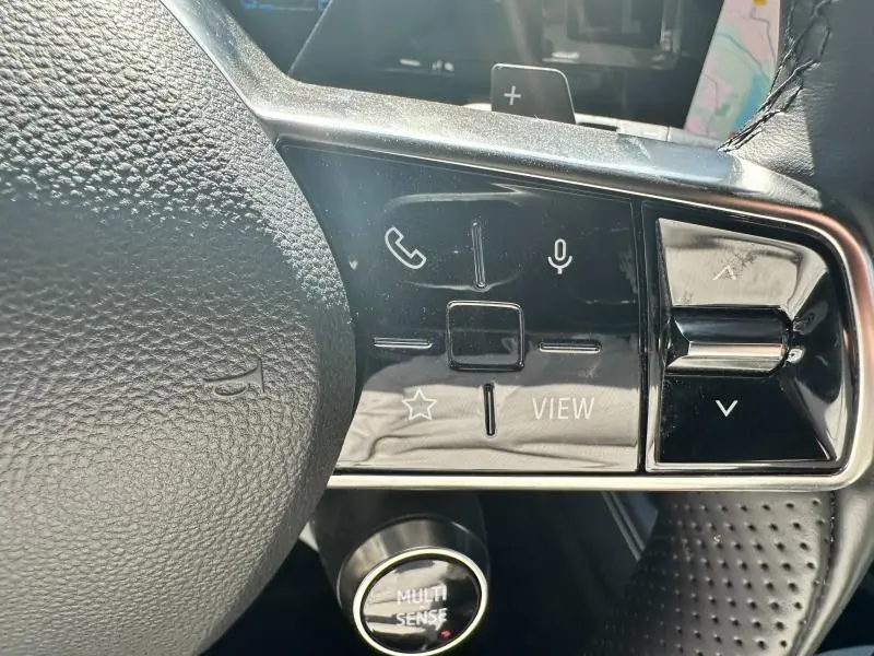 Gros plan sur les commandes gauche du volant cuir noir du Renault Espace gris Schiste 2024 avec bouton Multi Sense visible.