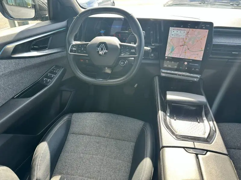 Vue intérieure avant du Renault Espace 2024 gris Schiste, volant cuir multifonction et écran tactile GPS central.