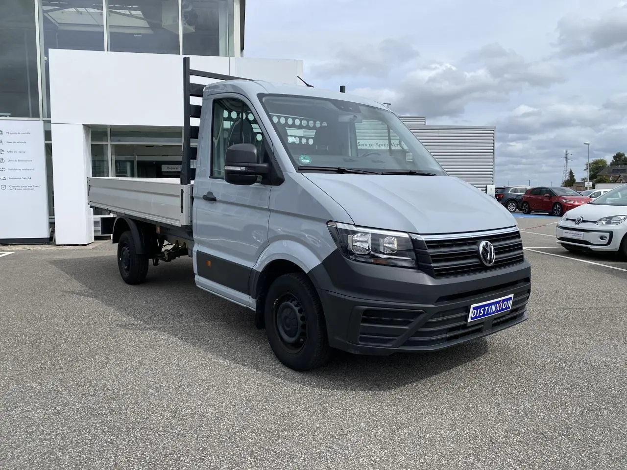 Volkswagen Crafter Fourgon gris argent vu en 3/4 avant droit avec plateau et ridelles aluminium rabattables.