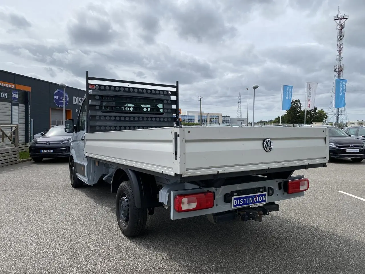 Vue 3/4 arrière droite d'un Volkswagen Crafter fourgon gris argent avec plateau et dispositif d'attelage rigide visible.