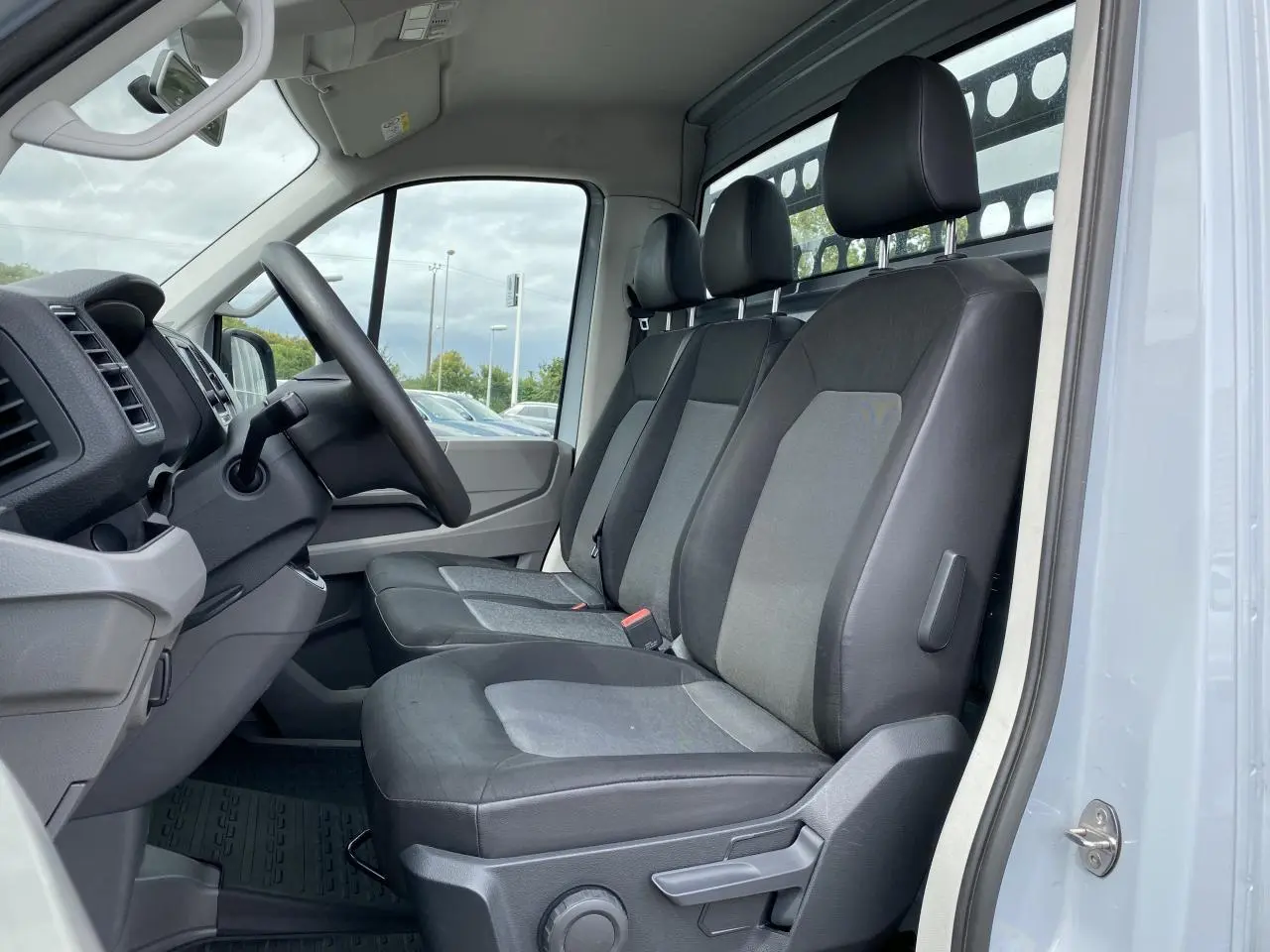 Vue intérieure côté conducteur du Volkswagen Crafter Business Line 2020 avec sellerie tissu gris et tableau de bord noir.