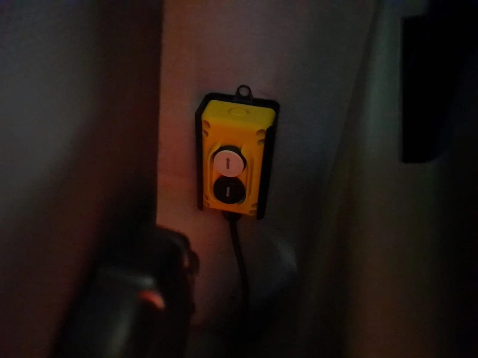 Télécommande jaune avec deux boutons fléchés, fixée à l'intérieur d'une Renault Master blanche 2024, vue rapprochée.