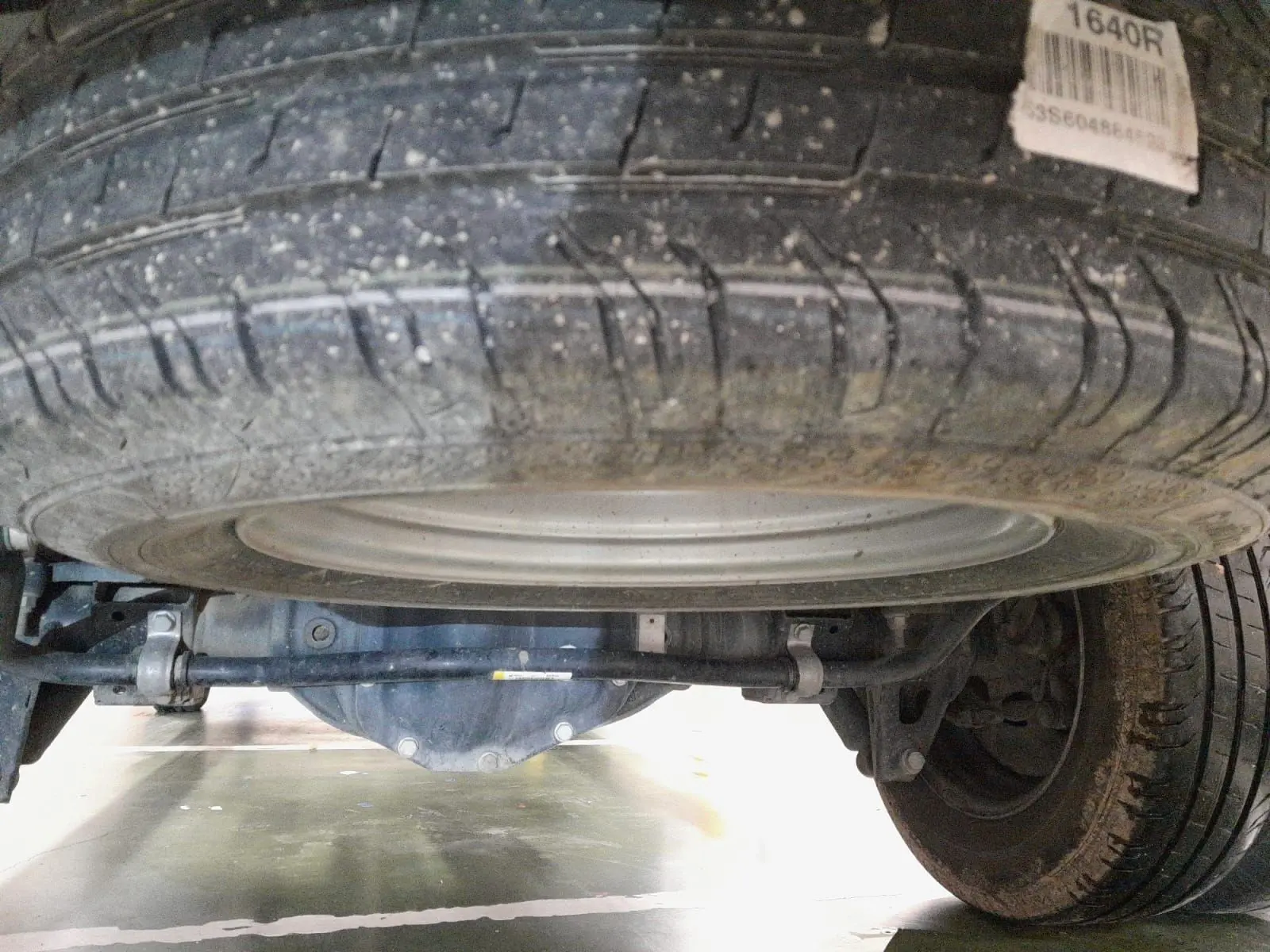 Vue en contre-plongée sous le Renault Master blanc 2024, montrant la roue de secours et le train arrière.