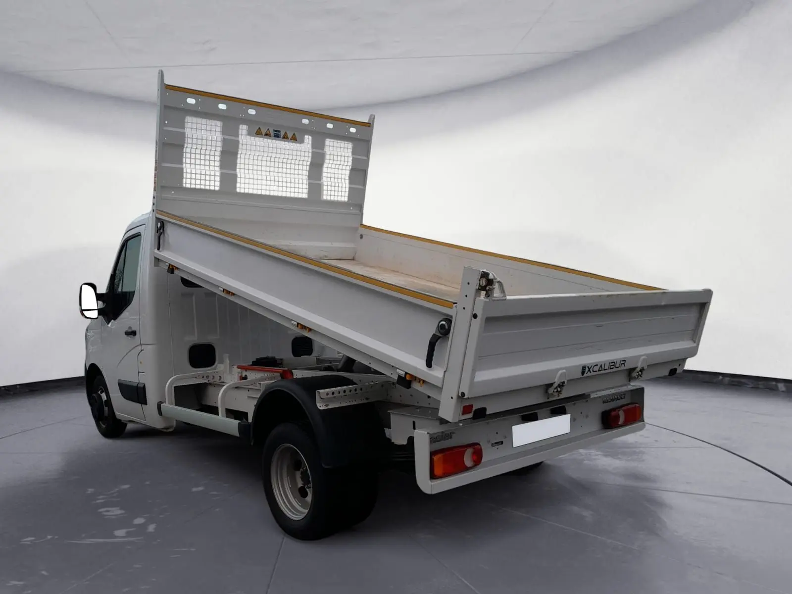 Renault Master blanc vue 3/4 arrière droit avec benne relevée et grille de protection arrière.