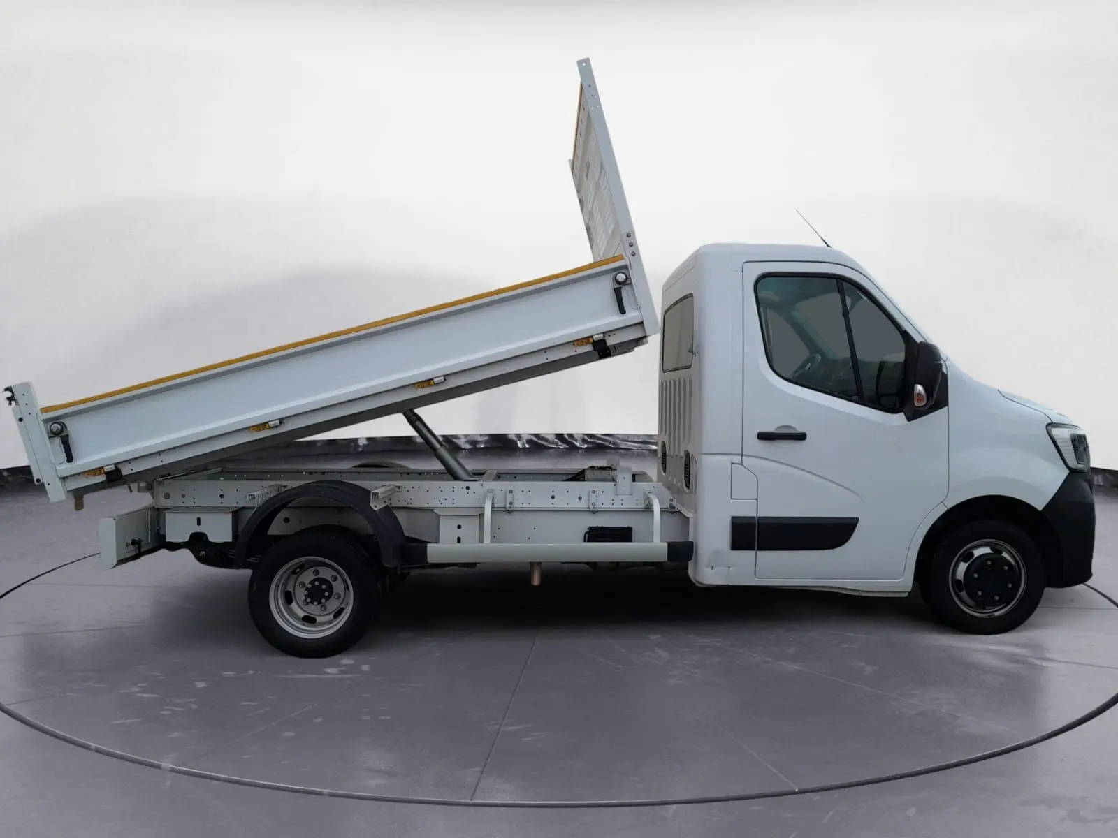 Vue de profil côté droit d’un Renault Master blanc 2024 avec benne basculante relevée.