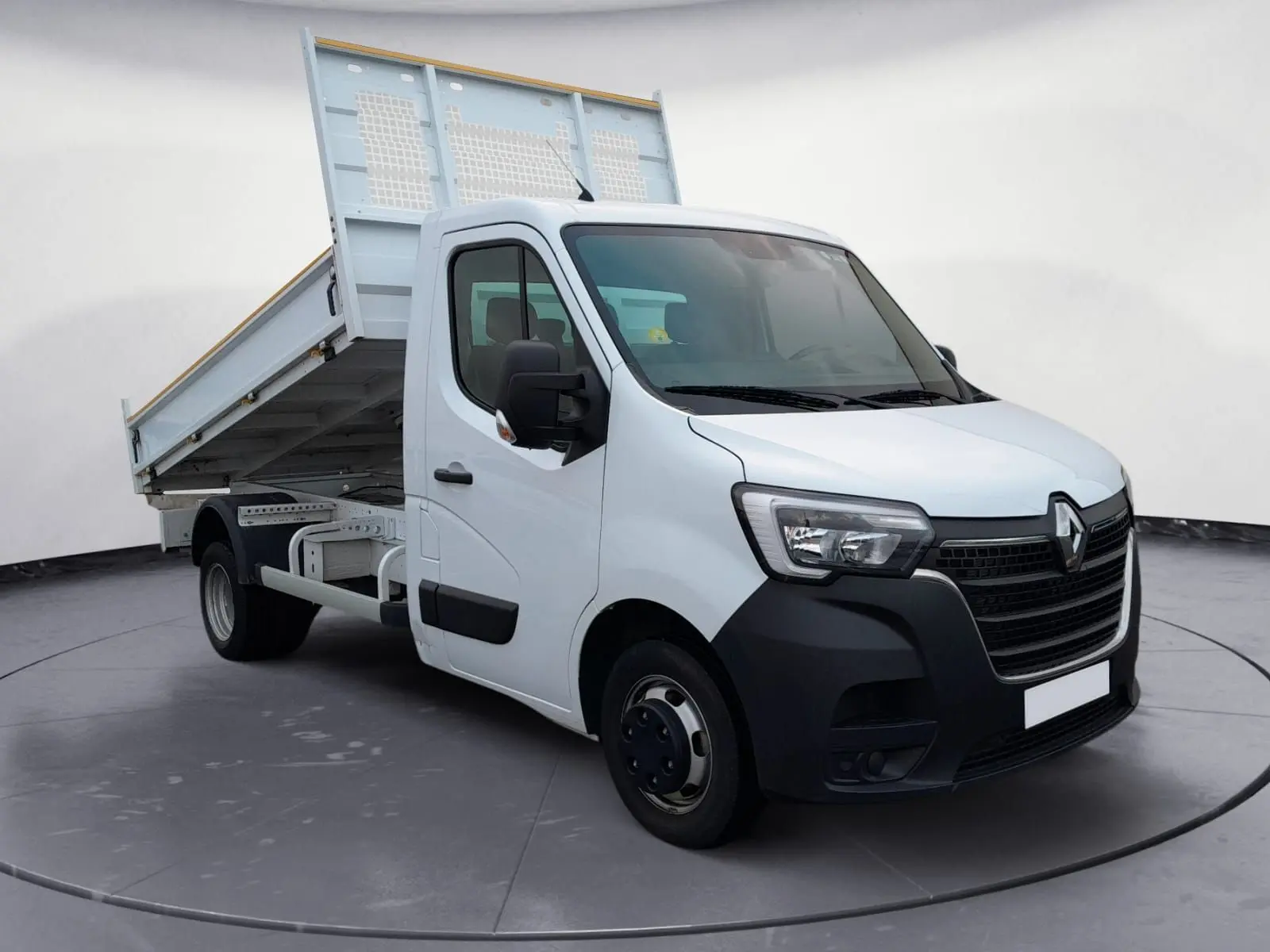 Renault Master blanc vue 3/4 avant droit avec benne relevée, mettant en valeur la cabine et le plateau basculant.