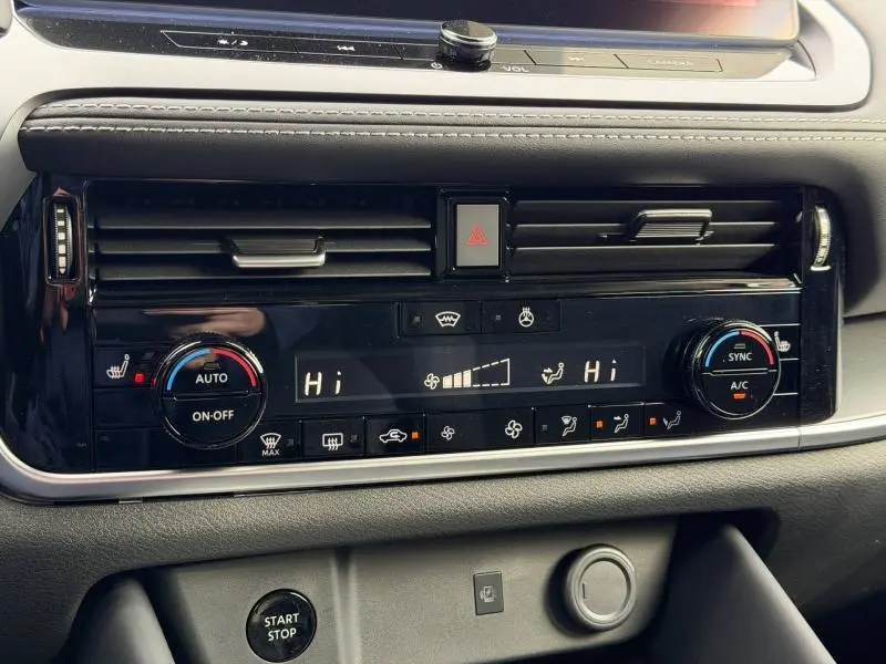 Détail du tableau de bord du Nissan Qashqai Hybrid e-POWER 2025 montrant la commande de climatisation bi-zone et les boutons de réglage.