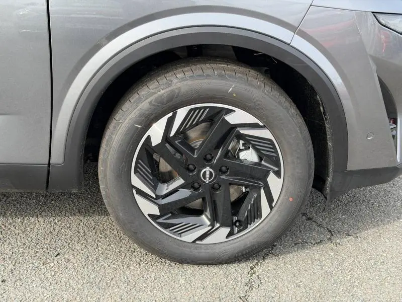 Gros plan sur la roue avant droite du Nissan Qashqai gris Squale Métallisé avec jante alu noire et argentée au design géométrique.