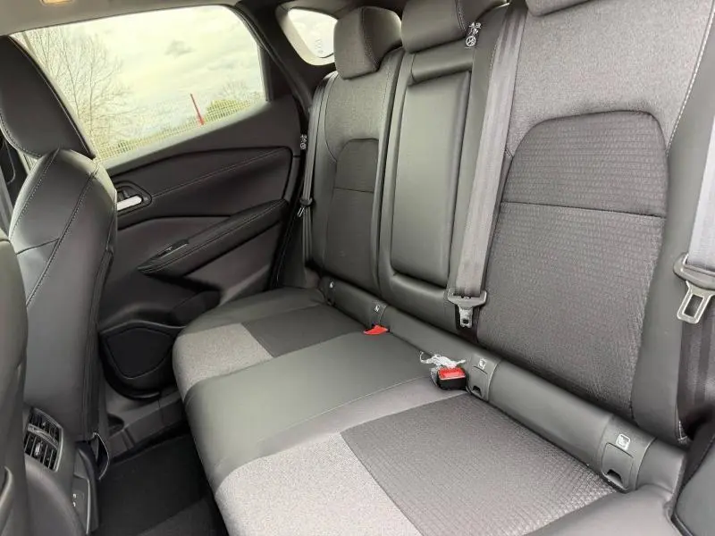 Vue intérieure arrière côté droit du Nissan Qashqai Hybrid e-POWER 2025, sièges mixtes TEP/tissu noirs avec accoudoir central.