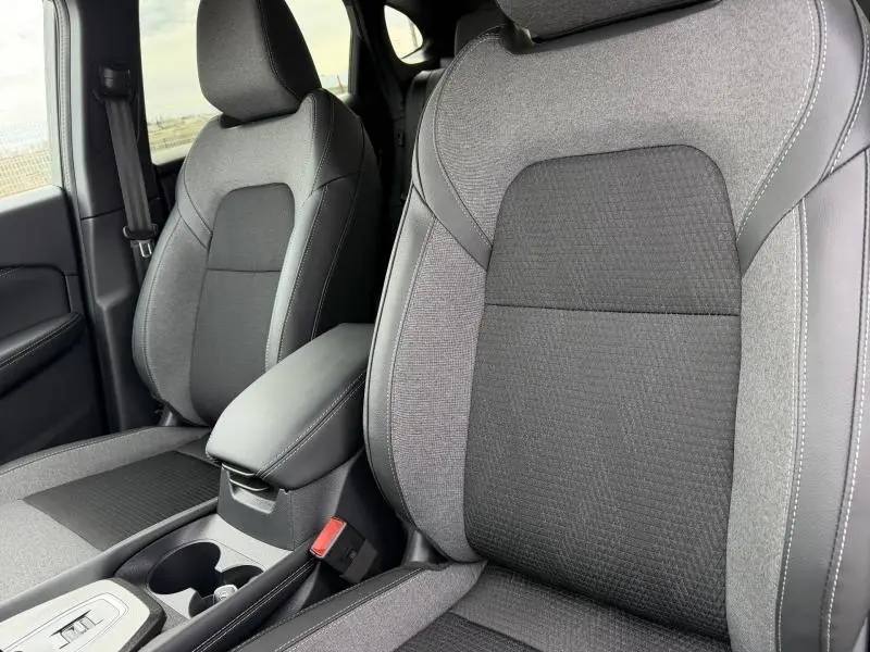 Gros plan sur les sièges avant gris et noirs du Nissan Qashqai Hybrid e-POWER 2025 avec accoudoir central.