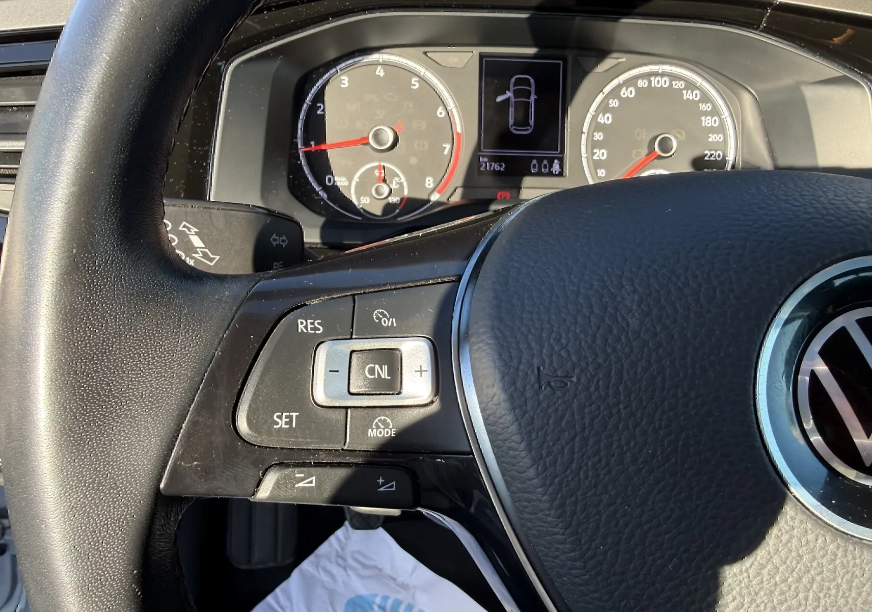 Vue rapprochée du volant noir et du tableau de bord numérique de la Volkswagen Polo gris métal, avec commandes au volant visibles.