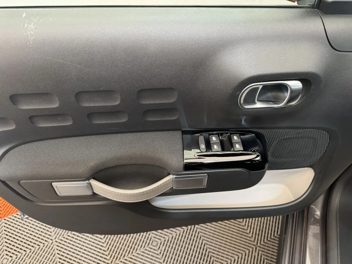 Vue rapprochée de la porte côté conducteur de la Citroën C3 gris foncé, avec commandes de vitres et poignée intégrée.