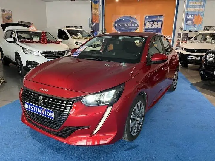 Peugeot 208 rouge Elixir métal vue 3/4 avant droit dans un showroom avec logo Distinxion visible.
