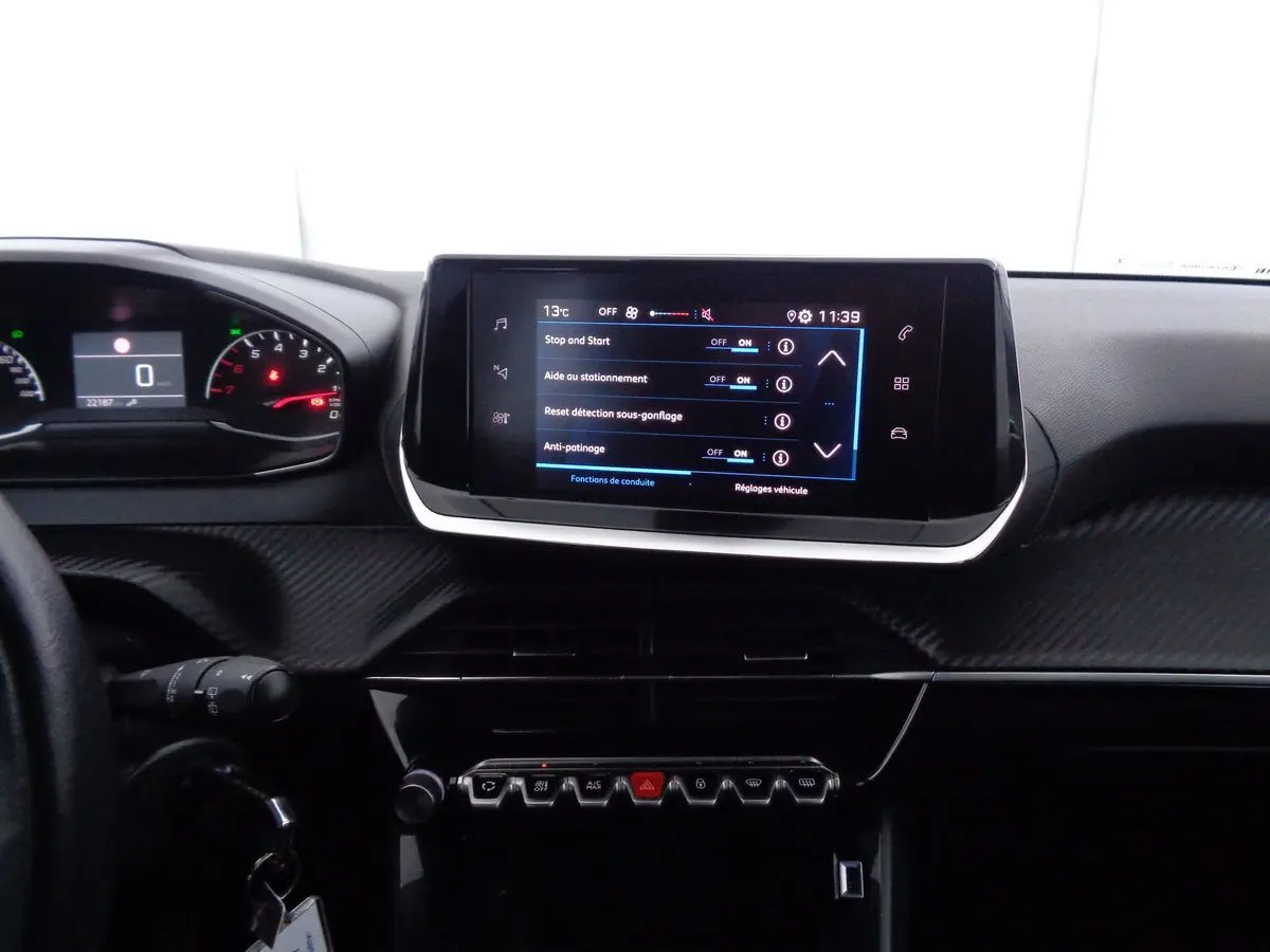 Tableau de bord et écran tactile central de la Peugeot 208 rouge Elixir, vue intérieure frontale détaillée.