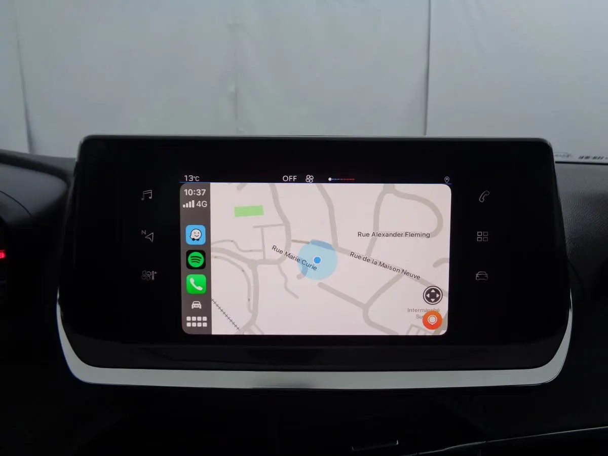 Écran tactile central affichant une carte de navigation dans l'habitacle d'une Peugeot 208 rouge Elixir Metal.