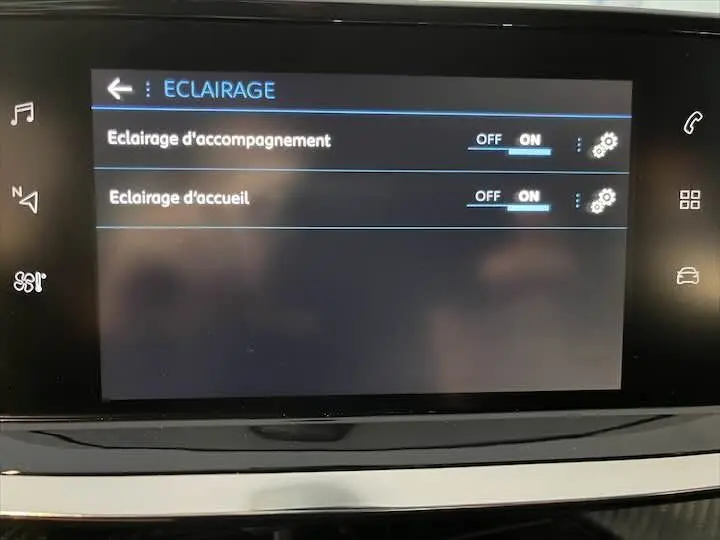 Écran tactile intérieur de la Peugeot 208 rouge Elixir Metal affichant les réglages d'éclairage d'accompagnement et d'accueil activés.