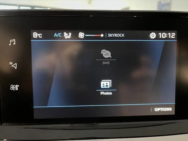 Écran tactile central de la Peugeot 208 rouge Elixir Metal affichant les options SMS et Photos à 10h12